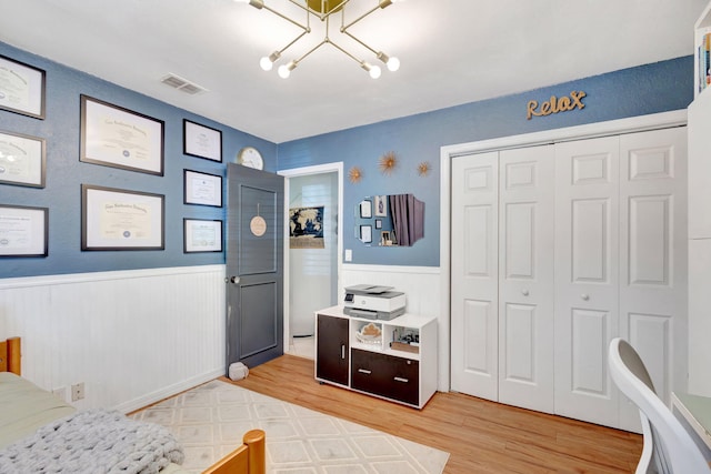 bedroom featuring visible vents, a closet, a wainscoted wall, and light wood finished floors