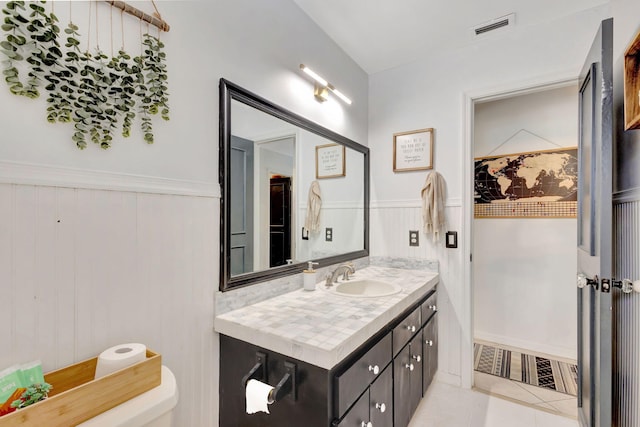 bathroom featuring tile patterned floors, visible vents, toilet, wainscoting, and vanity