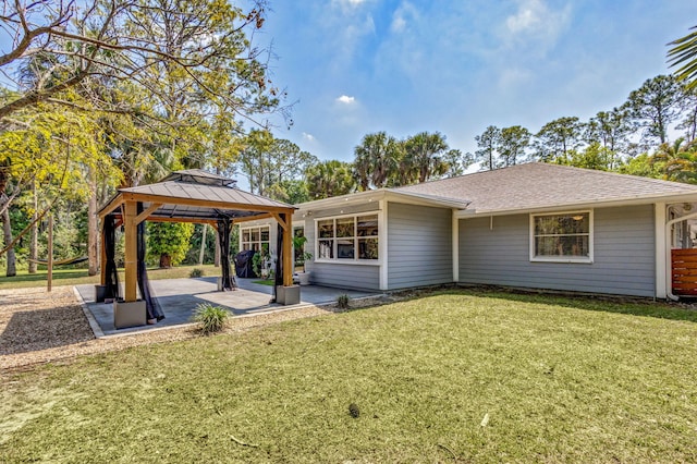 back of property with a gazebo, a patio, a lawn, and a shingled roof