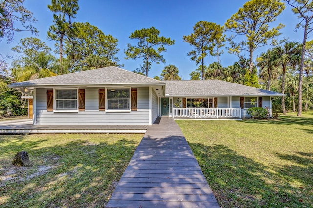 ranch-style home featuring a porch, a front lawn, and roof with shingles