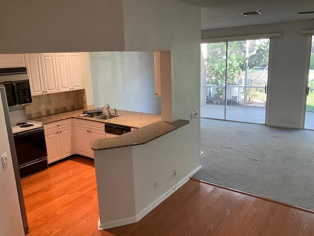 kitchen with a peninsula, a sink, dishwasher, light wood-style floors, and white cabinetry