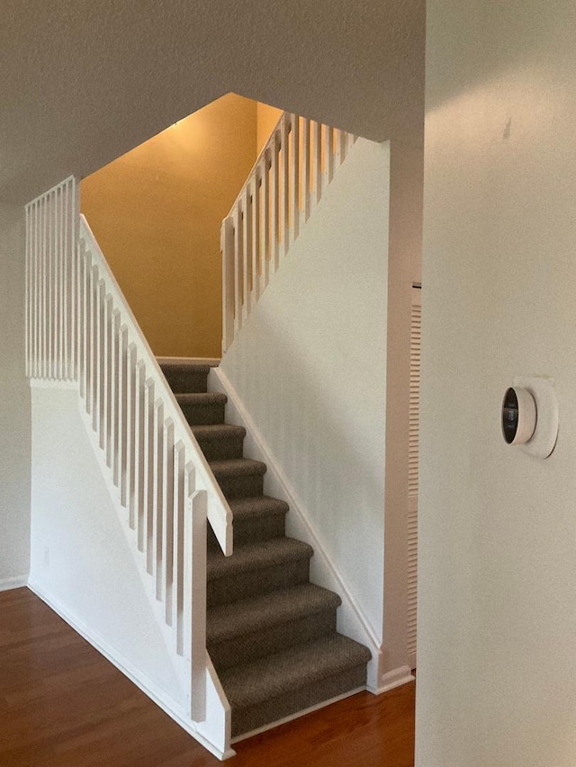 stairway with wood finished floors and baseboards