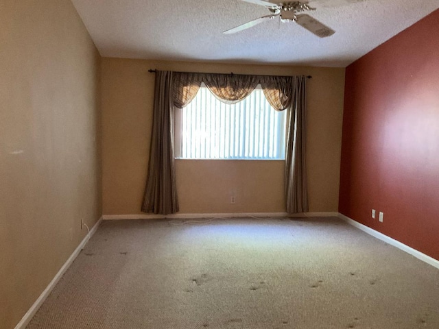 carpeted spare room featuring ceiling fan, baseboards, and a textured ceiling