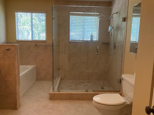 bathroom with toilet, a healthy amount of sunlight, a shower stall, and tile patterned flooring