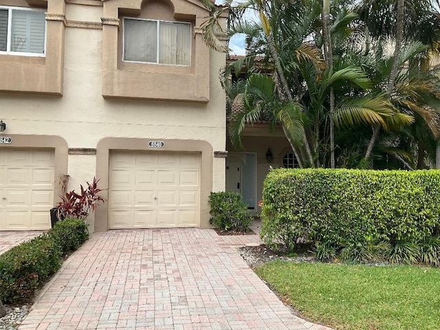 view of front of property featuring stucco siding, decorative driveway, and a garage