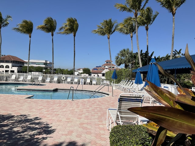 community pool with a patio area and fence