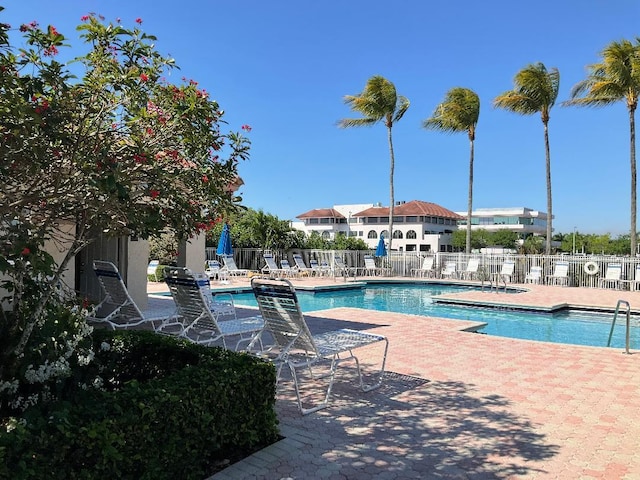 community pool with a patio area and fence