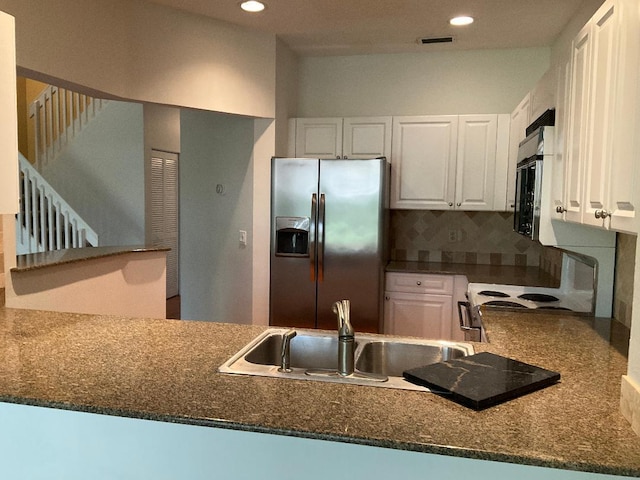 kitchen with range with electric cooktop, decorative backsplash, white cabinets, stainless steel fridge, and a sink