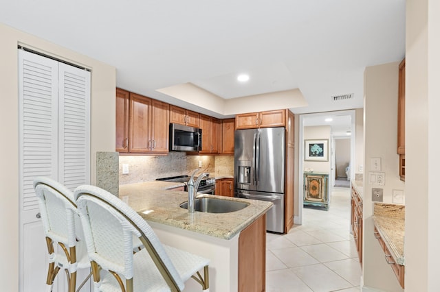 kitchen featuring visible vents, decorative backsplash, a peninsula, light tile patterned flooring, and stainless steel appliances