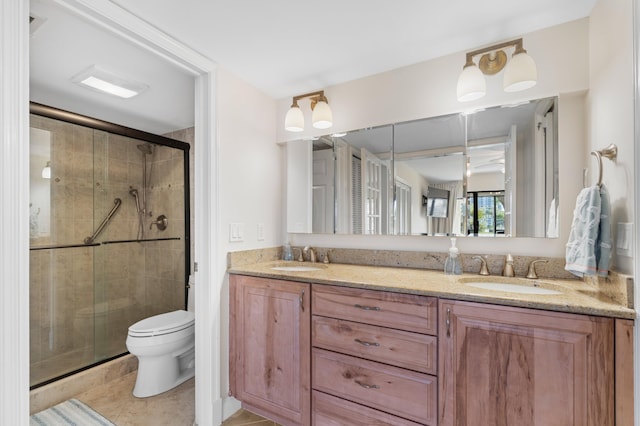 full bathroom featuring double vanity, a shower stall, toilet, and a sink