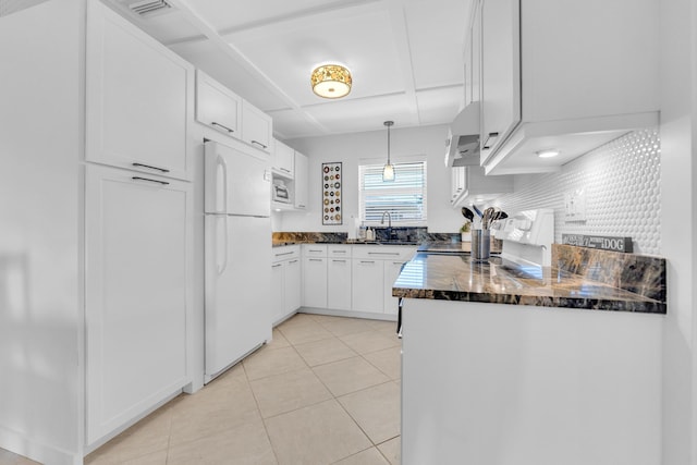 kitchen featuring stainless steel microwave, range with electric stovetop, freestanding refrigerator, light tile patterned flooring, and white cabinetry