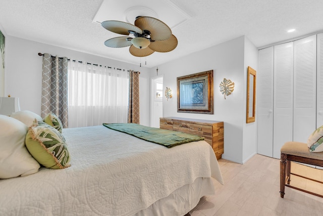 bedroom featuring light wood-type flooring, recessed lighting, a closet, a textured ceiling, and a ceiling fan