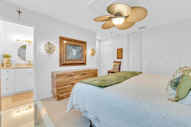 bedroom with ceiling fan, visible vents, light wood finished floors, and connected bathroom