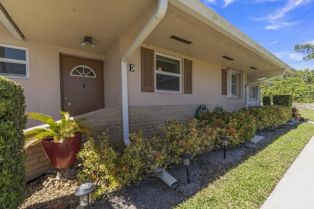 property entrance with brick siding and stucco siding