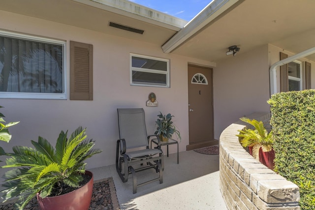 view of exterior entry with stucco siding and a patio