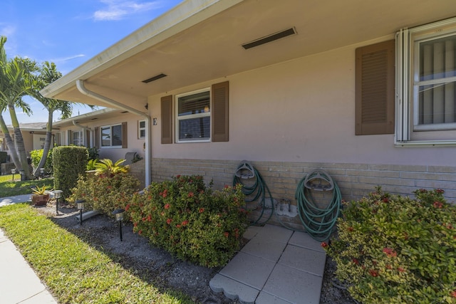 view of exterior entry featuring brick siding and stucco siding