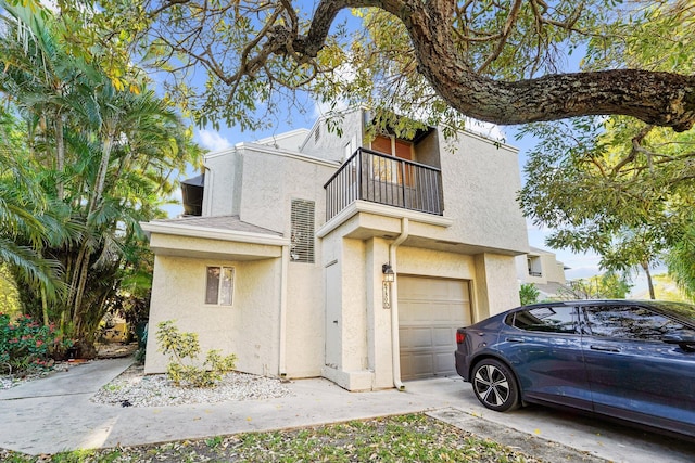 view of front facade featuring a balcony, stucco siding, concrete driveway, and a garage