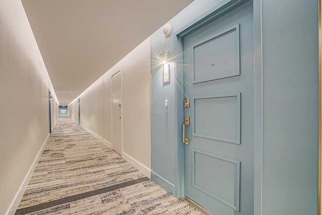 corridor featuring baseboards and wood finished floors