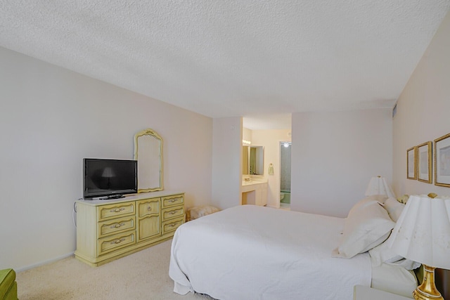 bedroom featuring light colored carpet, a textured ceiling, ensuite bathroom, and baseboards