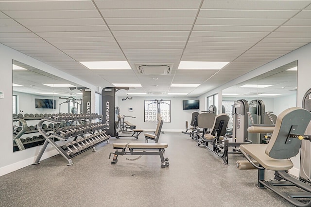 gym with a paneled ceiling and baseboards