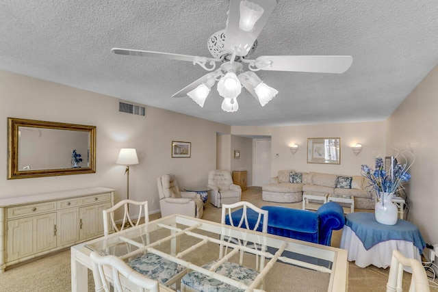 dining space with visible vents, light colored carpet, a textured ceiling, and ceiling fan