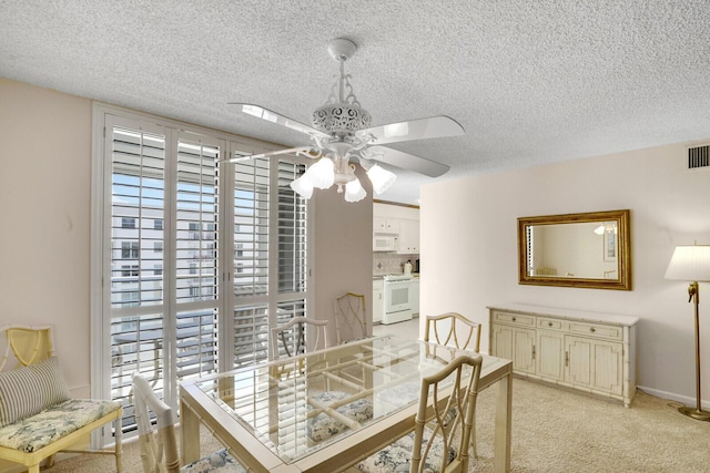 dining area featuring visible vents, light colored carpet, ceiling fan, and a textured ceiling