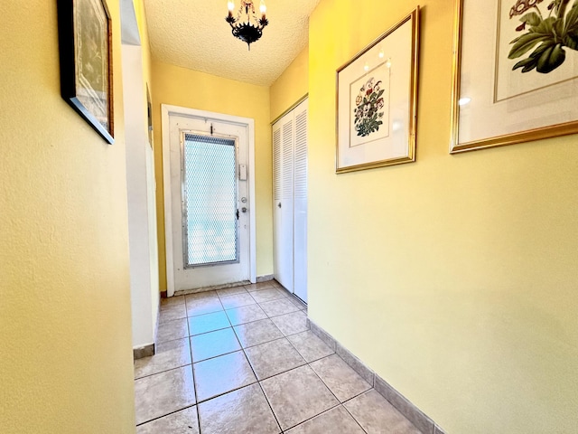 doorway to outside with light tile patterned floors, baseboards, and a textured ceiling