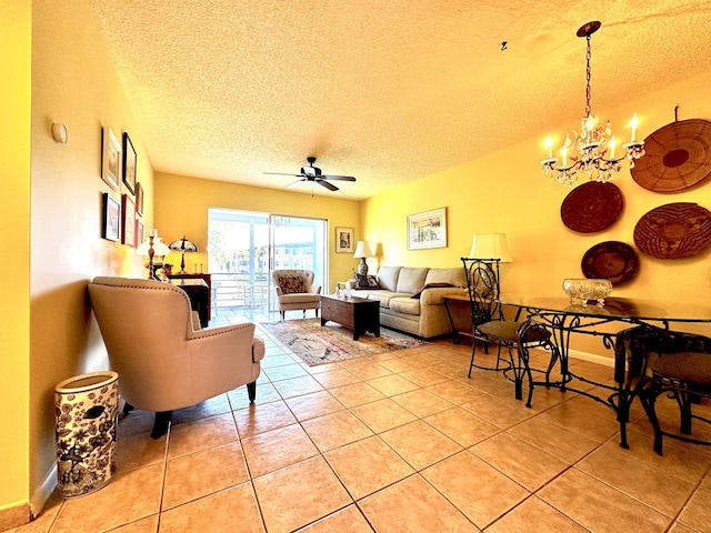 living area with light tile patterned floors, baseboards, a textured ceiling, and ceiling fan with notable chandelier