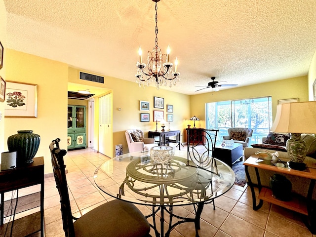 dining space featuring light tile patterned floors, visible vents, a textured ceiling, and ceiling fan with notable chandelier