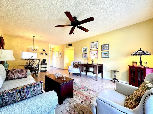 living area featuring visible vents, ceiling fan with notable chandelier, a textured ceiling, tile patterned flooring, and baseboards