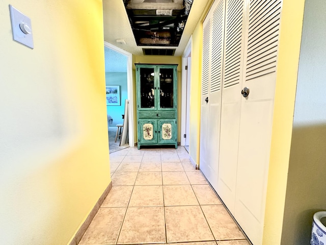 corridor featuring light tile patterned flooring and baseboards