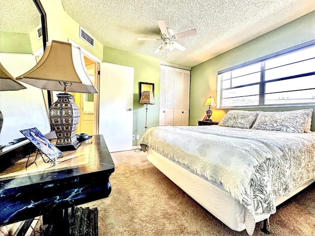 bedroom with visible vents, ceiling fan, carpet, a closet, and a textured ceiling