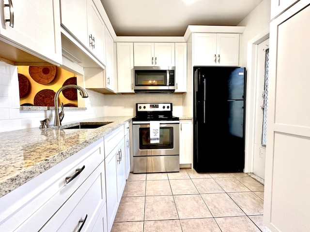 kitchen featuring decorative backsplash, appliances with stainless steel finishes, light tile patterned flooring, white cabinets, and a sink