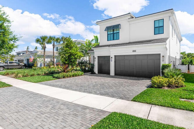 view of front of property with decorative driveway, a garage, and stucco siding