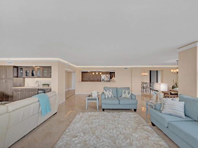 living room featuring a chandelier, visible vents, indoor wet bar, and ornamental molding