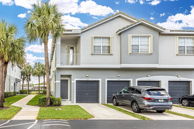 view of property with stucco siding, a garage, driveway, and a tiled roof