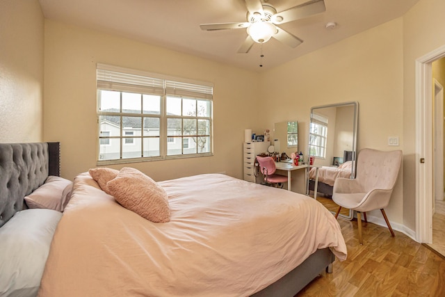 bedroom with light wood finished floors, multiple windows, a ceiling fan, and baseboards