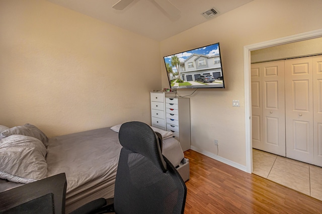 bedroom with a ceiling fan, visible vents, baseboards, light wood-style floors, and a closet