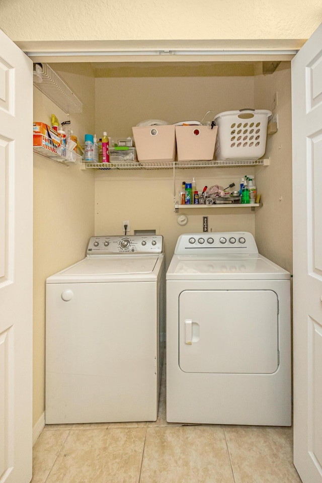 laundry area with laundry area, light tile patterned flooring, and washing machine and dryer