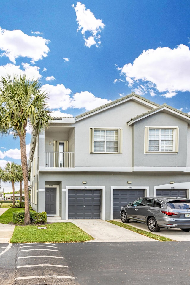 townhome / multi-family property featuring a balcony, an attached garage, and stucco siding