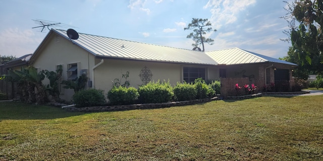 exterior space with a standing seam roof, an attached garage, stucco siding, a front lawn, and metal roof