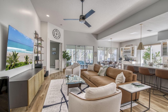 living room featuring visible vents, recessed lighting, ceiling fan, light wood-style floors, and a textured ceiling