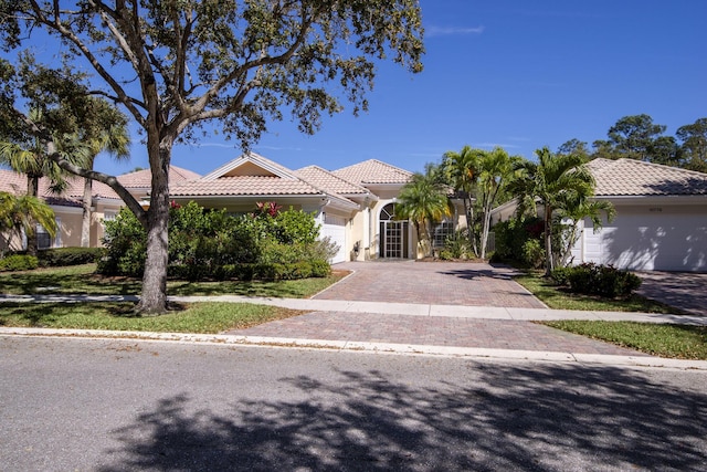 mediterranean / spanish-style house featuring a tiled roof, decorative driveway, and a garage