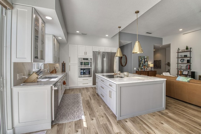 kitchen featuring light wood-style flooring, a sink, glass insert cabinets, white cabinetry, and black electric cooktop