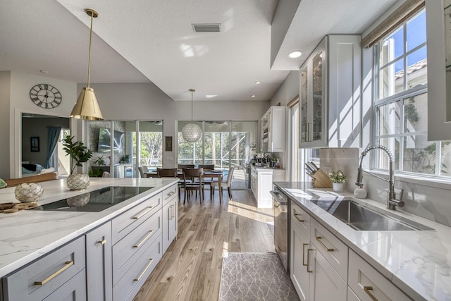 kitchen featuring light wood-type flooring, visible vents, a sink, stainless steel dishwasher, and black electric cooktop