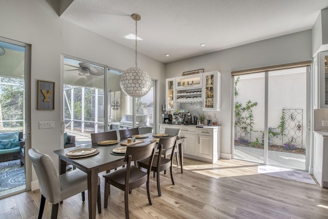 dining room featuring recessed lighting, light wood-type flooring, and a textured ceiling