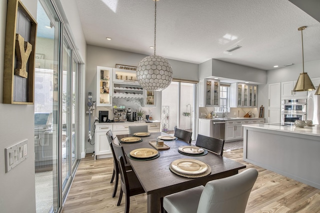 dining room featuring visible vents, light wood finished floors, and a textured ceiling