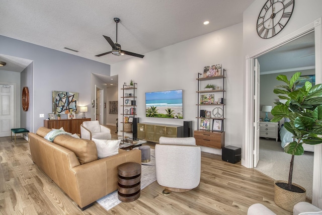 living area featuring visible vents, a textured ceiling, light wood-style flooring, and a ceiling fan