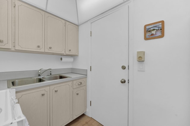 kitchen with cream cabinetry, range, light countertops, and a sink