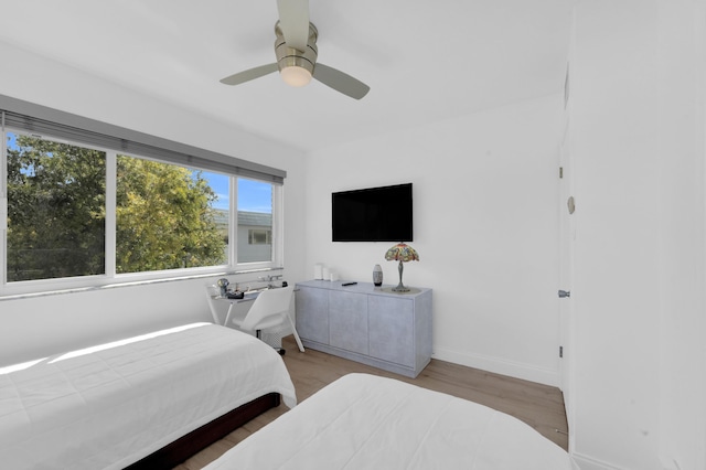 bedroom featuring baseboards, wood finished floors, and a ceiling fan